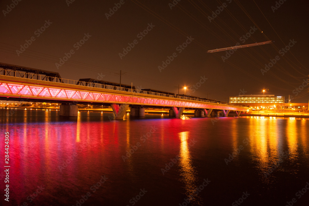 Glowing red light rail bridge over water
