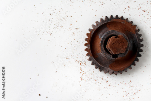 Rusty bolt, nut and gear wheel made of chocolate isolated on white background. Chocolate chip scattered on smooth surface. Mechanic gearing background. Father's day card obects. Copy space for text