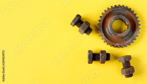 Rusty bolts, nuts and gear wheel made of chocolate isolated on bright yellow background. Mechanic gearing background. Father's day card obects photo