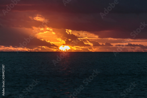 Pacific Ocean, French Polynesia, Society Islands, Leeward Islands, Bora Bora. View of sun setting over ocean creating a bright orange sky.