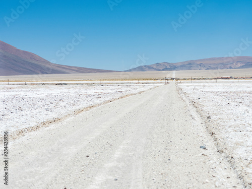 The salt flats Salar de Pocitos in the Argentinian Altiplano. Routa 27 is crossing the salt flats, Pocitos village in the background. Argentina.