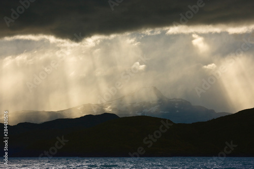 Chile  Torres del Paine National Park. A curtain of rain creates crepuscular rays of light as storm moves across Lake Pehoe. 