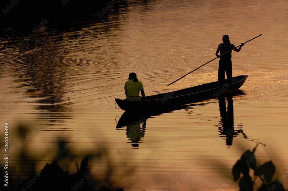 Quichua Indians poling dugout canoe on jungle lake. Amazon Rain Forest. Ecuador. South America