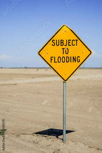 USA, California, Central Valley, San Joaquin River Valley, Angiola, Rt 43 sign 'Subject to Flooding' next to raised aqueduct