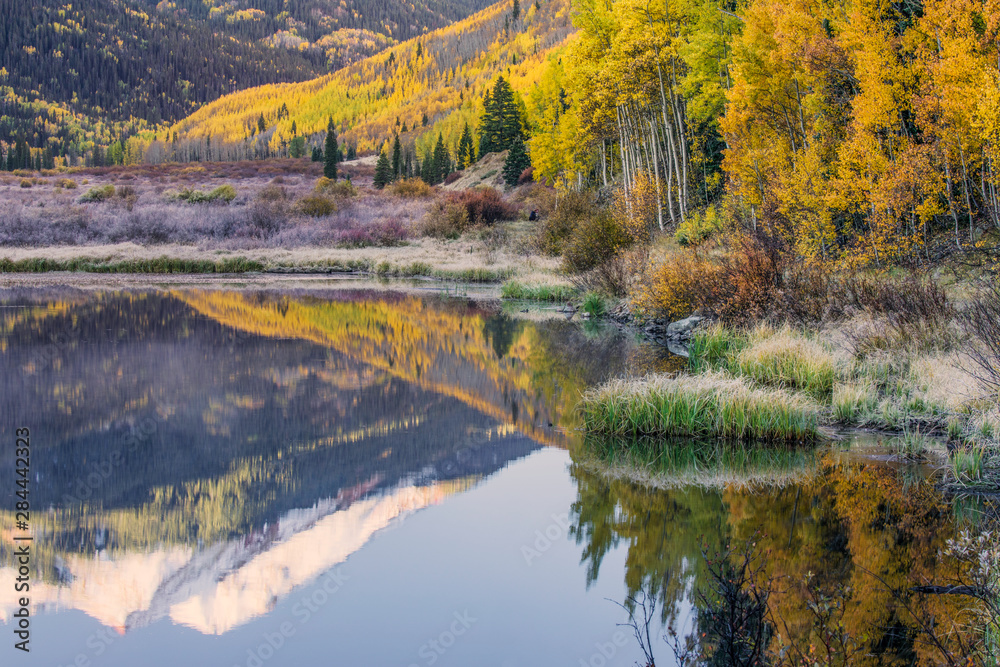 Fototapeta premium Fall colors and Red Mountain reflected on Crystal Lake at sunrise, near Ouray, Colorado