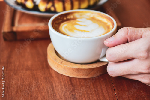 Close up Hand holding coffee cup of  People are in coffee shop