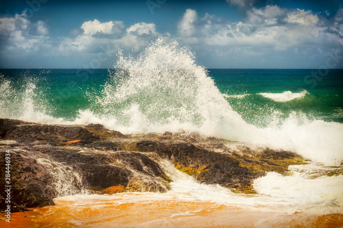 USA, Kauai, Hawaii. A wave breaks on the rocks at Kauapea Beach, popularly known as Secret Beach. photo