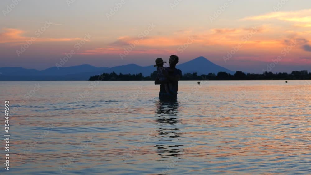 Baby girl bathing in the sea with father. Father's love concept. Child care leave background. Father with baby in the sea. Loving father playing with toddler in the water. part of series Baby girl bathing in the sea with father. Father's love concept. Child care leave background. Father with baby in the sea. Loving father playing with toddler in the water. part of series