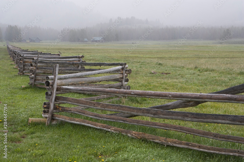 USA, Idaho, Sawtooth Mountains. Split-rail fence divides field in misty farm country. 