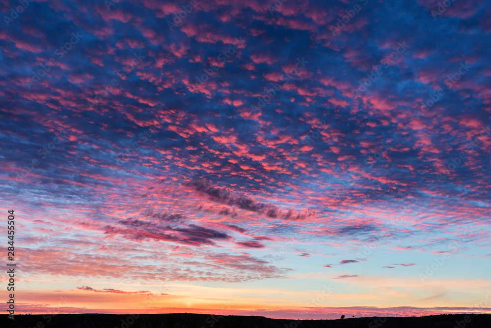 Fototapeta premium Vivid sunrise clouds over badlands formation in Theodore Roosevelt National Park, North Dakota, USA