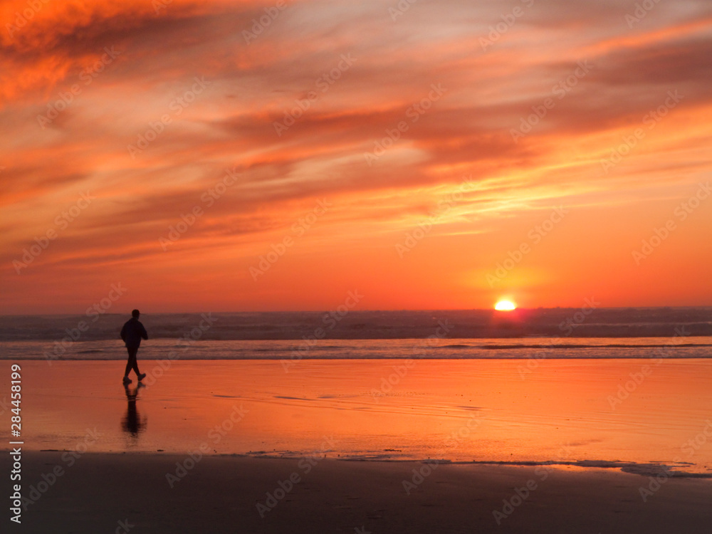 USA, Oregon, Cannon Beach. Man walks along beach at sunset. 