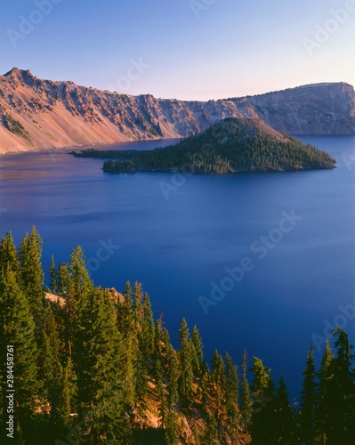 USA, Oregon, Crater Lake National Park. Sunrise on west rim of Crater Lake with Hillman Peak (left) and Llao Rock (right) overlooking Wizard Island.