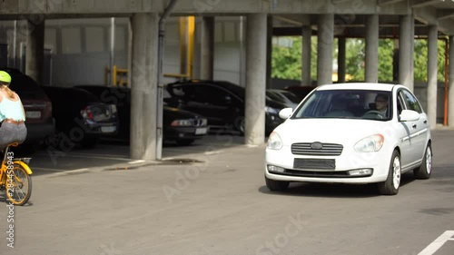 Fearless teenager riding bike right in front of car, driver stopping on time