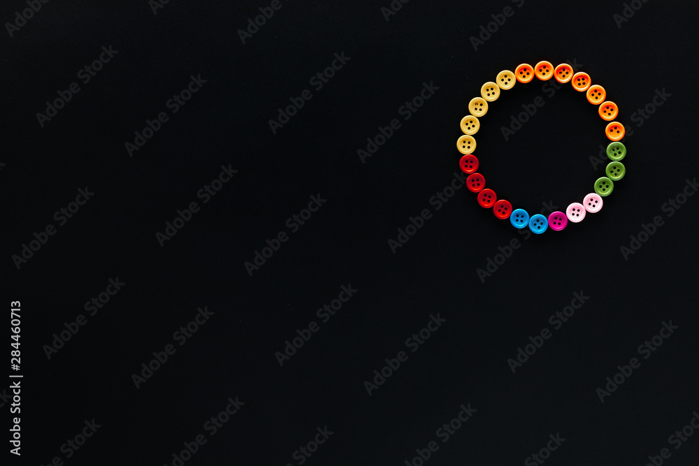 A circle made from buttons on black background, shot from above , arranged at the top right. A circle made from buttons on black background, shot from above , arranged at the top right.