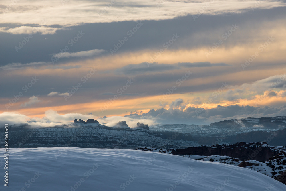 USA, Utah. Clouds and mist enveloped cliffs and valley covered in snow at sunset.