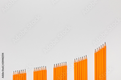 A bunch of pencils arranged in columns in an ascending order on white background  shot from above.