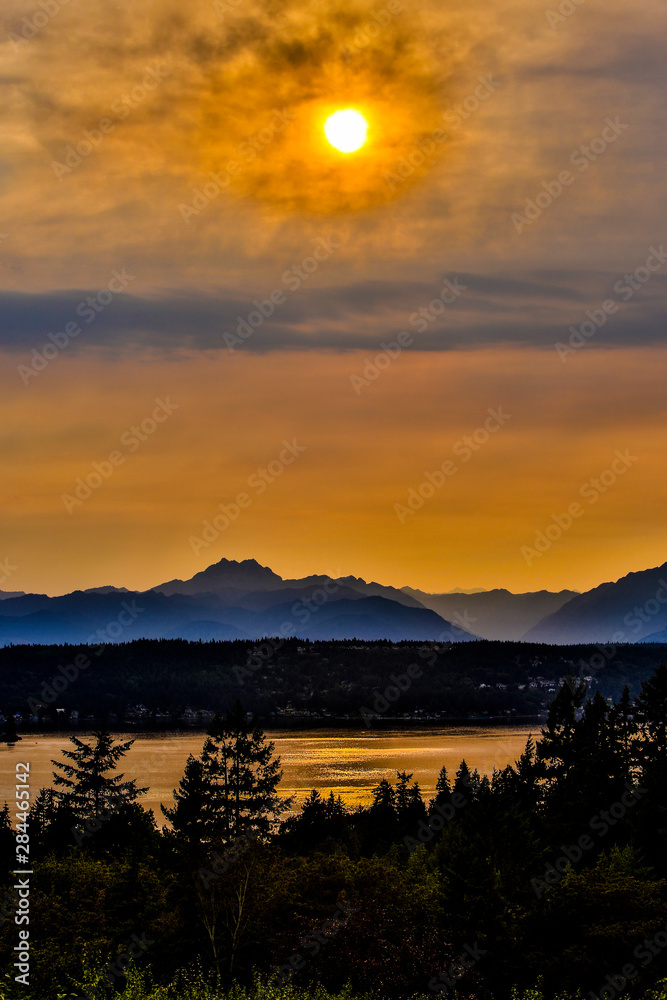 Bremerton, Washington State. The Brothers Mountain and the Olympic Mountains overlook Dyes Inlet, as the sun begins to set, casting a golden glow on the water