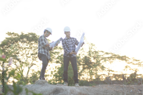 blurry silhouette portrait of two engineers or architects pointing at the golden sky for copyspace