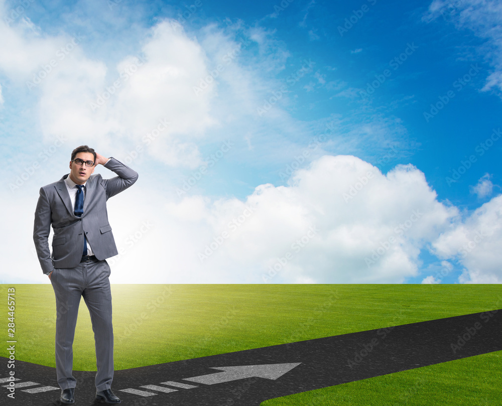 Young businessman at crossroads in uncertainty concept Young businessman at crossroads in uncertainty concept