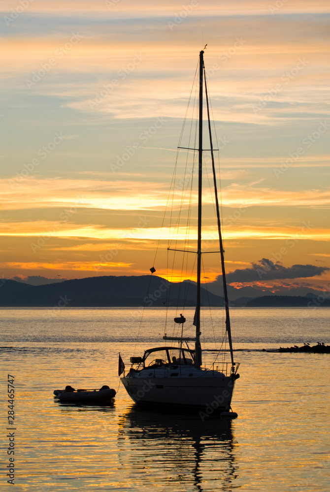 USA, WA, San Juan Islands. Sailboat at mooring silhouetted by sunset