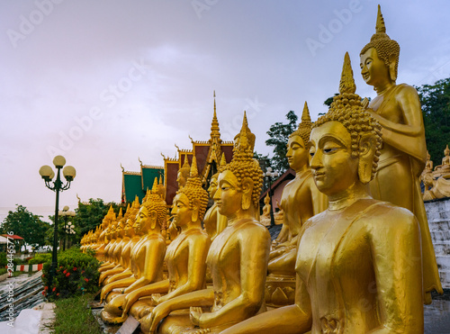 The golden Buddha statue of Phu Salao temple with Mekong River flows through the Pakse city in beautiful sunset moment at Pakse, Laos photo