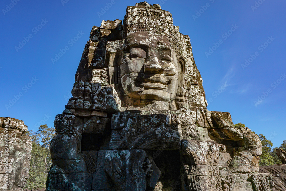Detail Mural faces in the stone of Bayon belong angkor thom nearly angkor wat is popularity of the site among tourists with blue sky in background. UNESCO World Heritage Site. Siem Reap, Cambodia