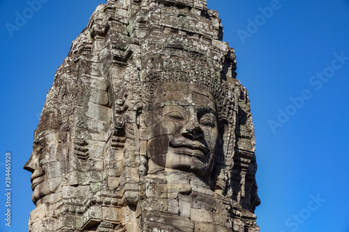 Detail Mural faces in the stone of Bayon belong angkor thom nearly angkor wat is popularity of the site among tourists with blue sky in background. UNESCO World Heritage Site. Siem Reap, Cambodia