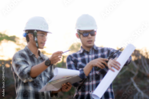 blurry portrait of two engineer's or architect's dress with hardhat, safety helmet have a meeting at outdoor on sunrise or sunset time photo
