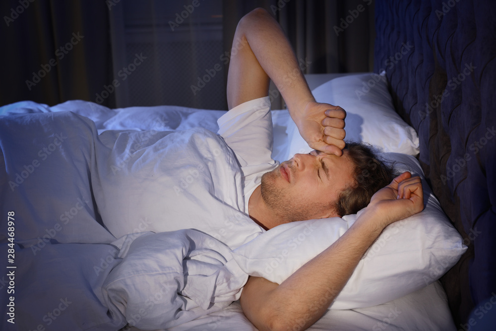 Sleepy young man lying under blanket at night. Bedtime Sleepy young man lying under blanket at night. Bedtime