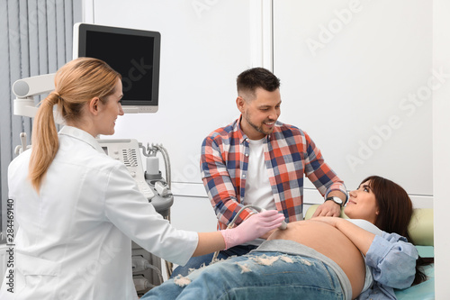 Man supporting his wife during ultrasound scan in clinic