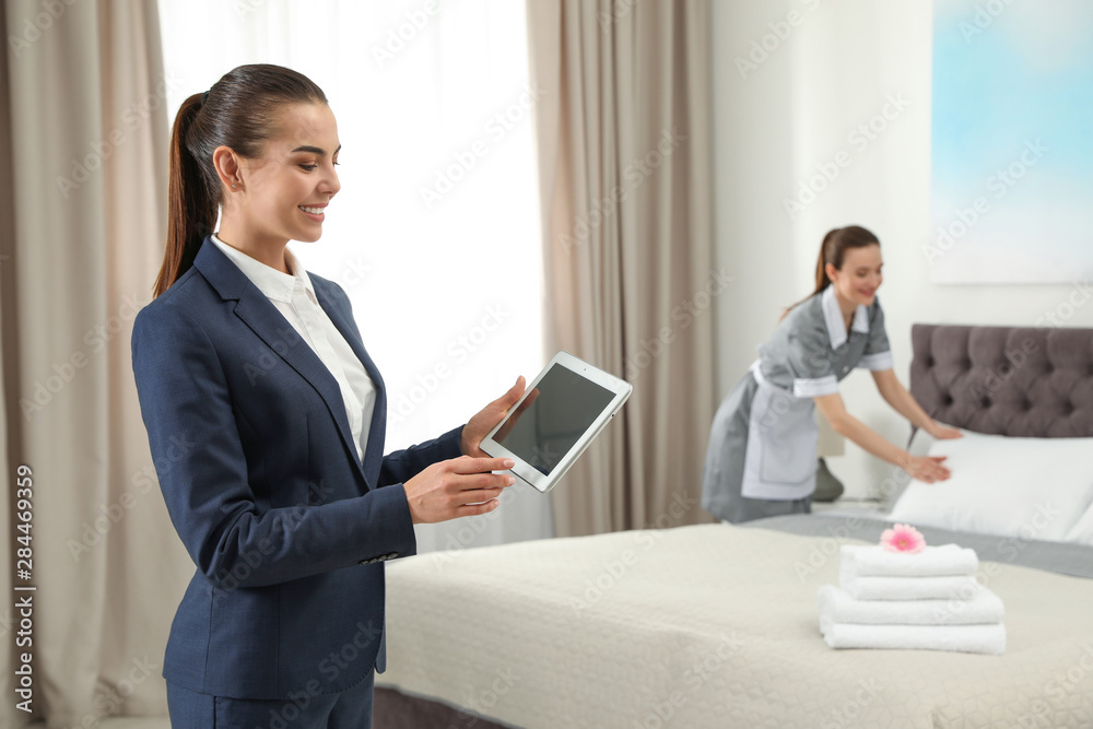 Housekeeping manager with tablet checking maid work in hotel room. Space for text Housekeeping manager with tablet checking maid work in hotel room. Space for text