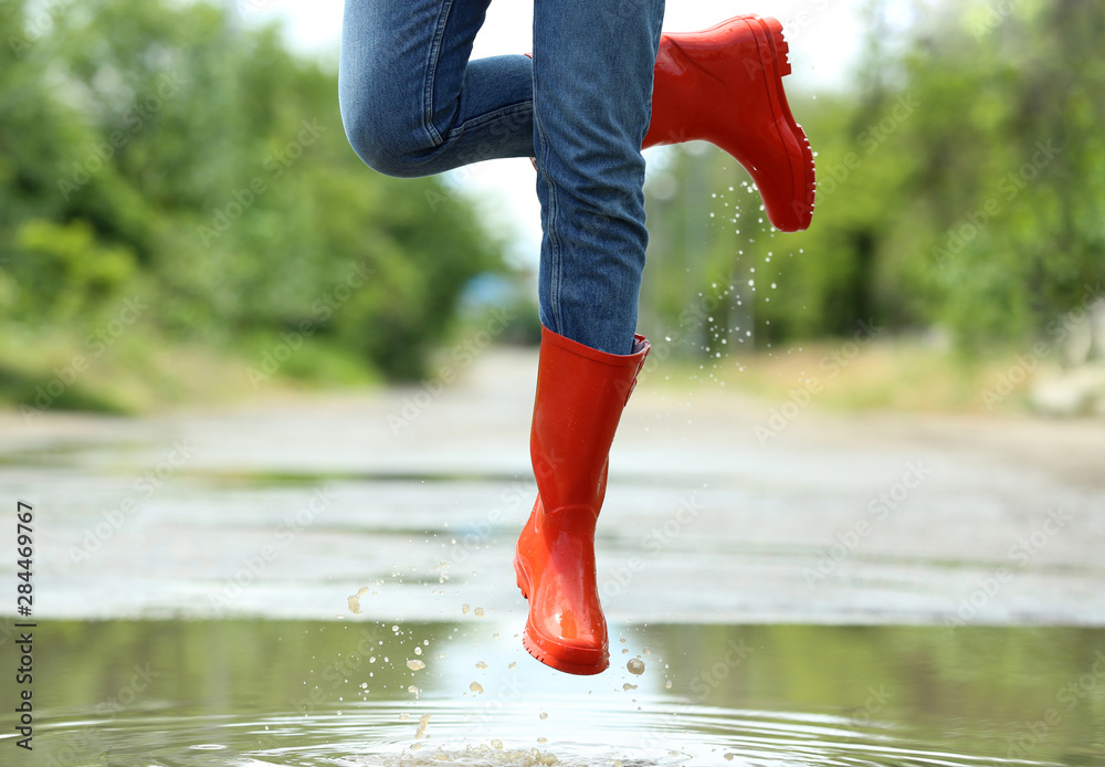 Woman with red rubber boots jumping in puddle, closeup. Rainy weather  Photos | Adobe Stock