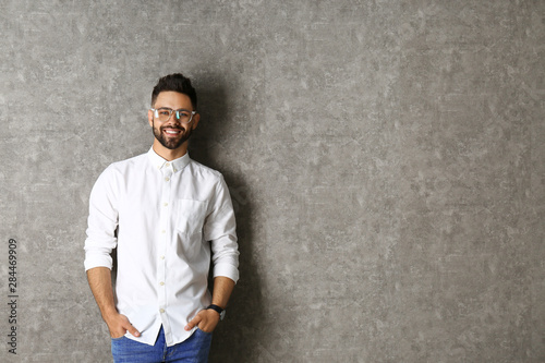 Portrait of handsome smiling man in glasses on grey background. Space for text