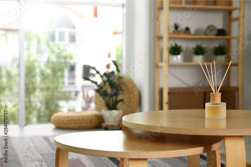 Reed diffuser on wooden table in modern room interior