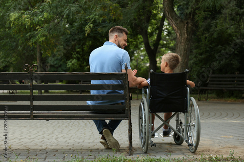 Fotografering Father with his son in wheelchair at park