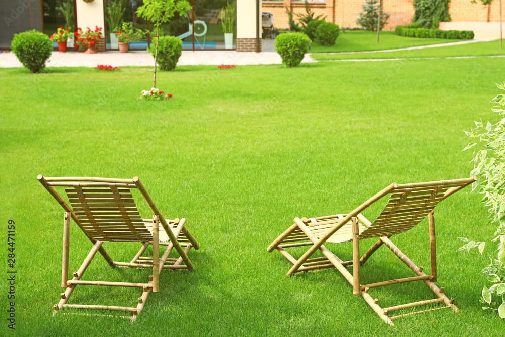 Wooden deck chairs in beautiful garden on sunny day Wooden deck chairs in beautiful garden on sunny day