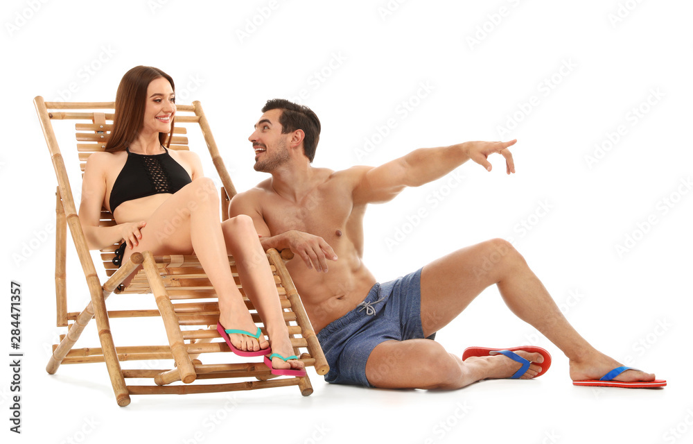Young couple with sun lounger on white background. Beach accessories