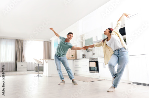 Beautiful couple dancing in kitchen at home