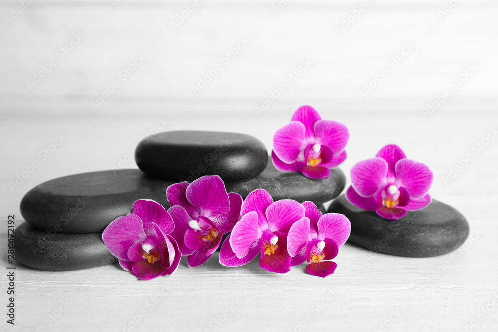 Spa stones and orchid flowers on white wooden table Spa stones and orchid flowers on white wooden table