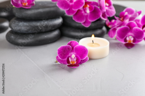 Spa stones  orchid flowers and candle on grey background