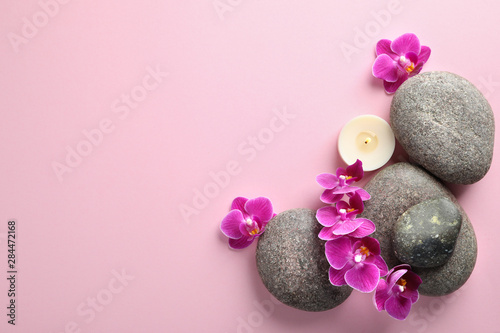 Flat lay composition with spa stones and orchid flowers on pink background. Space for text