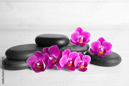 Spa stones and orchid flowers on white wooden table