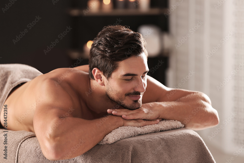 Obraz premium Handsome young man relaxing on massage table in spa salon