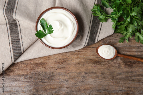 Flat lay composition with sour cream and parsley on wooden table, space for text photo