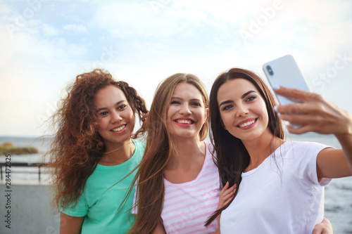 Happy young women taking selfie outdoors on sunny day