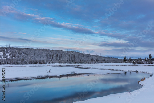 Sunrise clouds reflecting into the Madison River in winter in Yellowstone National Park, Wyoming, USA