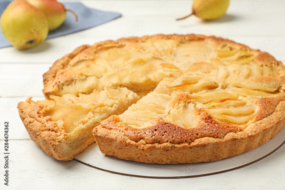 Cut delicious sweet pear tart on white wooden table, closeup