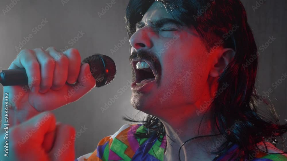 Man with mustache and mullet from the 70s 80s 90 singing with a mic in his hand. Vintage concept.