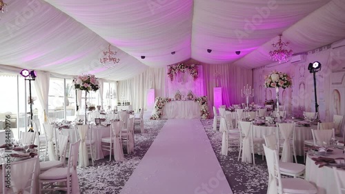 back motion along gorges banquet hall decorated for wedding party with fresh flowers and white furniture slow motion