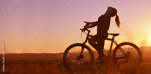 Silhouette of a girl on a bicycle in the sunset. Healthy lifestyle concept.